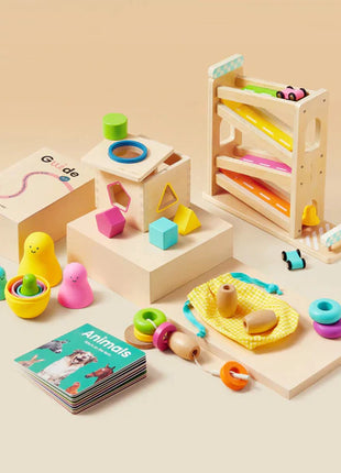 The Tiny Land® Montessori Complete Baby Set (0-24 months) includes colorful wooden and silicone toys for sensory play and fine motor skills: stacking rings, shape sorter, ball ramp, teethers, nesting cups, Animals board book, and play guide.