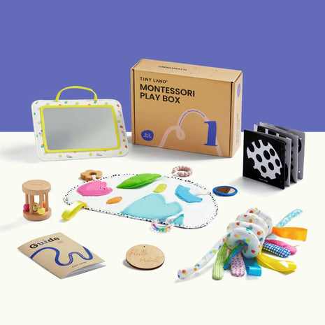 The Tiny Land® Montessori Complete Baby Set (0-24 months) includes a play box, mirror, wooden rattle, and sensory mat—perfect for sensory play and fine motor development—all displayed on a white surface with a purple background.